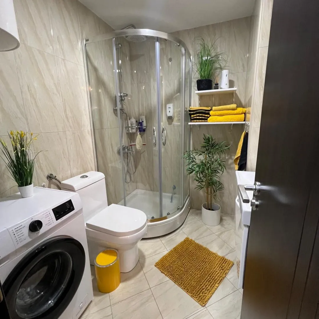 Compact bathroom with a shower cabin, toilet, and washing machine.