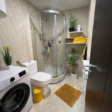 Compact bathroom with a shower cabin, toilet, and washing machine. - image 8