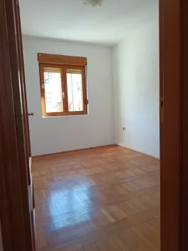 Empty room with wooden parquet flooring and a window, viewed through an open doorway. - image 2