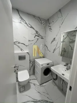 Moderno kupatilo sa mermernim pločicama, toaletom, umivaonikom i mašinom za veš. - image 11