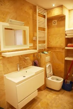 Kupatilo obloženo žutim mermerom sa bijelim umivaonikom, WC šoljom i ogledalom. - image 12