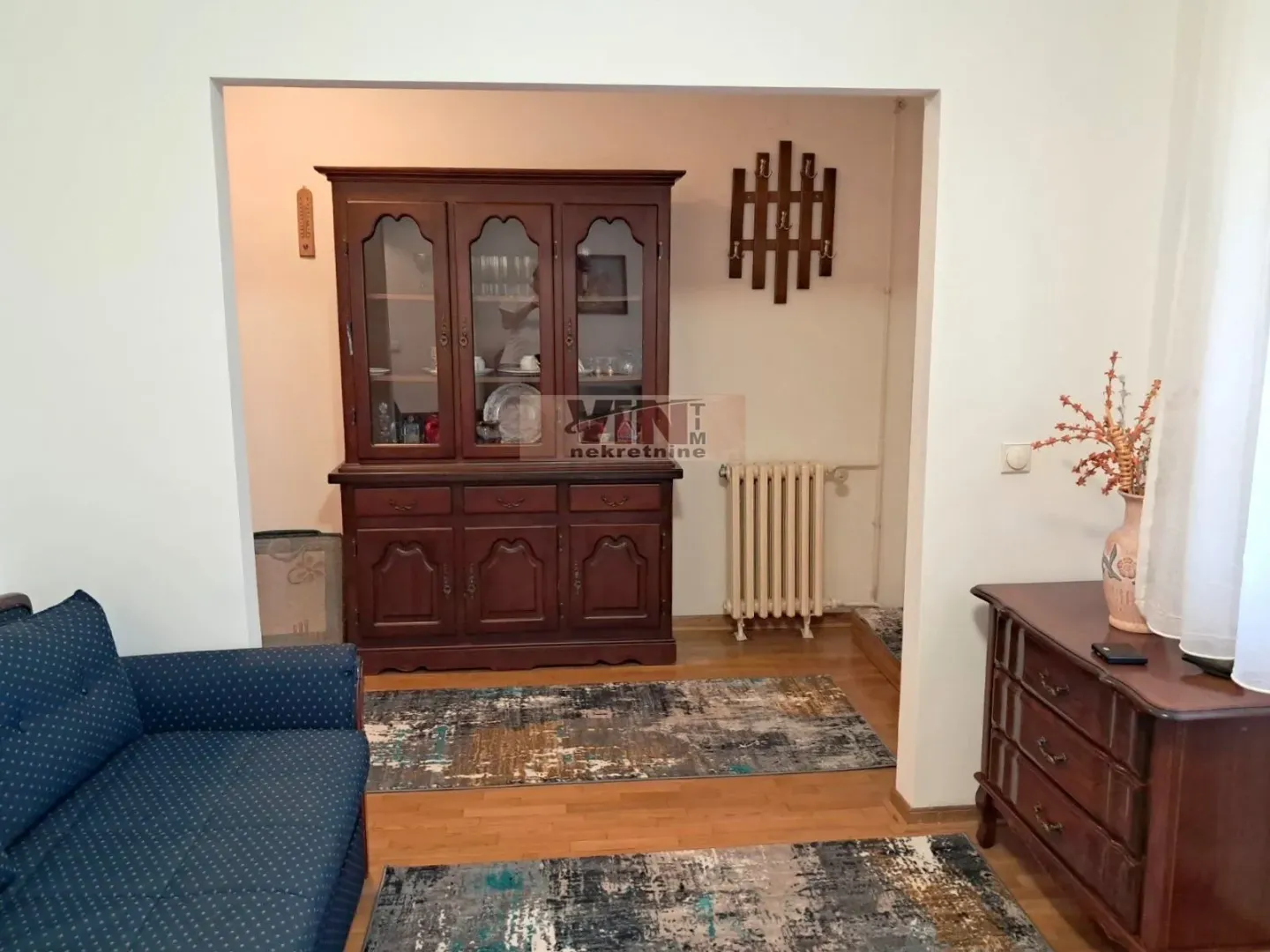 Living room with wooden furniture, a sofa, and rugs.