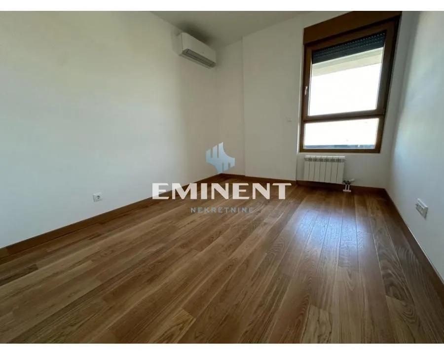 Empty room with wooden flooring, an air conditioning unit, and a window.