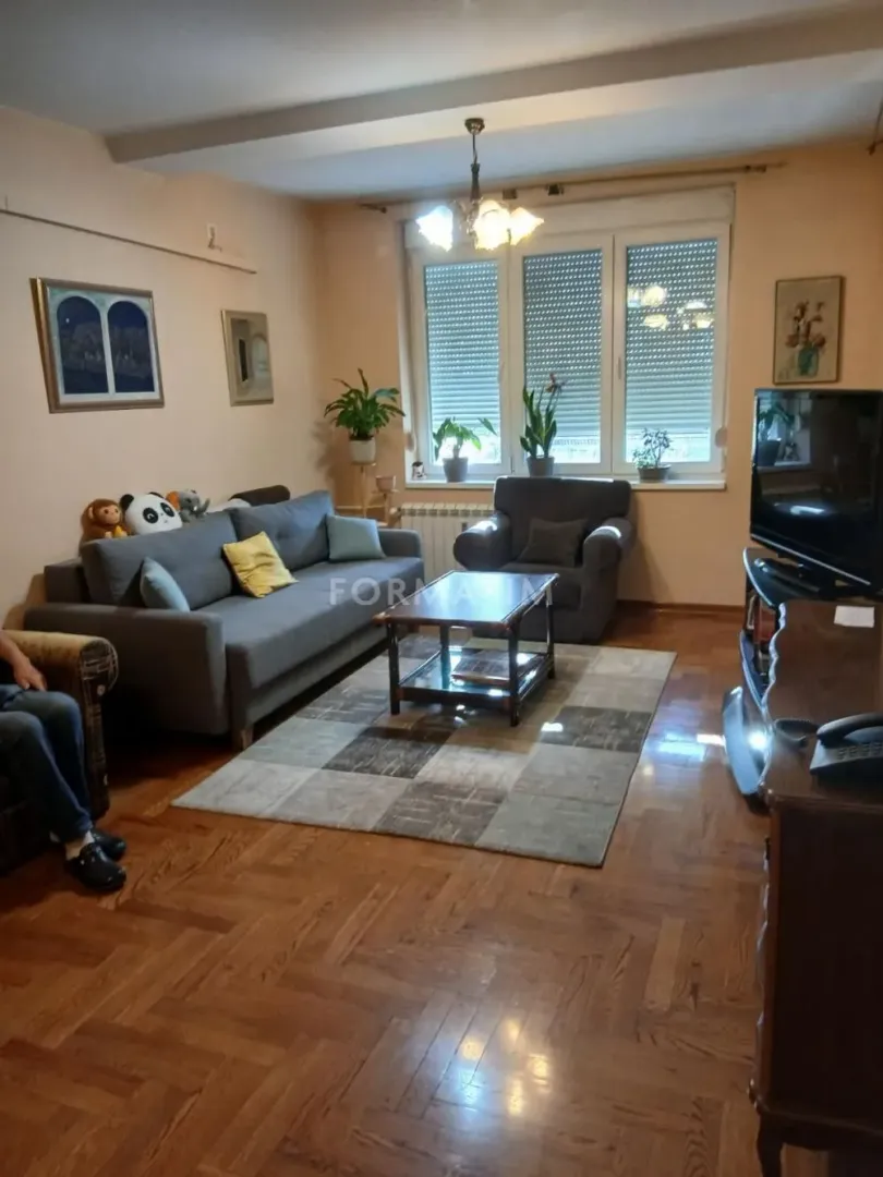 Dnevna soba sa garniturom, stočićem i televizorom.