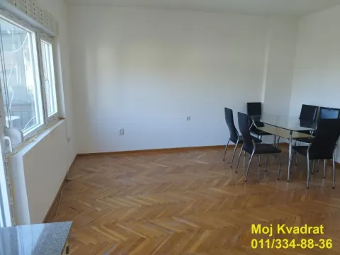 Dining area with a glass table and black chairs in a room with parquet flooring. - image 2