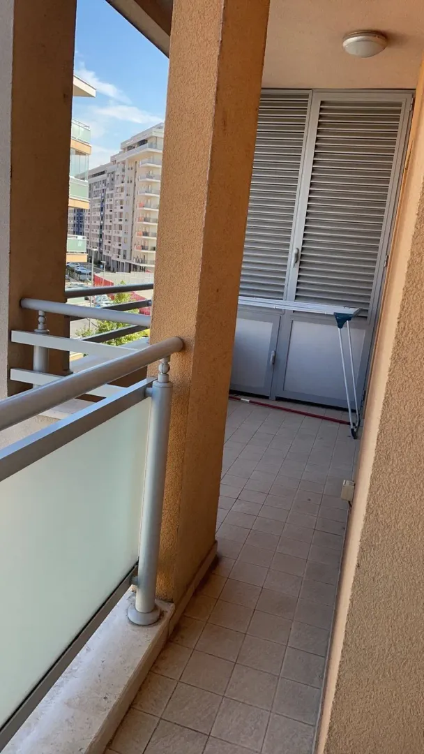 Uski balkon sa pločicama i pogledom na grad.