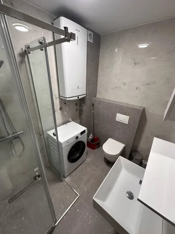Savremeno opremljeno kupatilo sa tuš kabinom, veš mašinom i bojlerom.