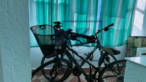 Bicycles placed on a balcony with green curtains. - image 11