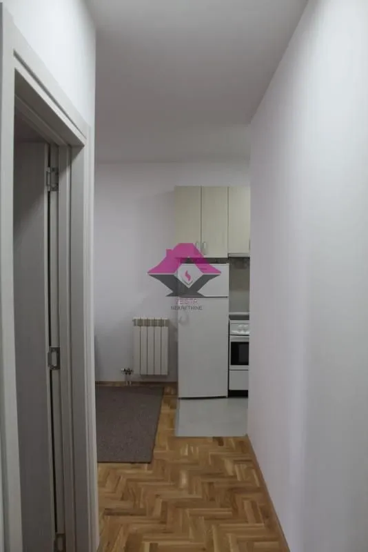 View from the hallway into a small kitchen with white cabinets and appliances.