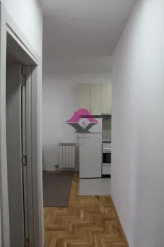 View from the hallway into a small kitchen with white cabinets and appliances. - image 7
