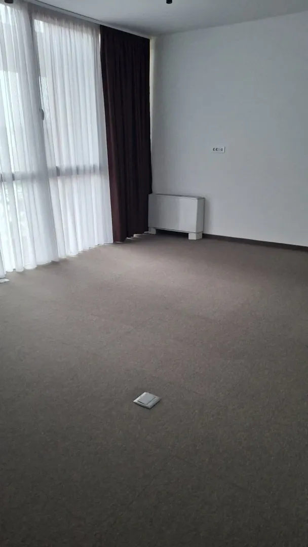 Empty room with carpet flooring and a large window.