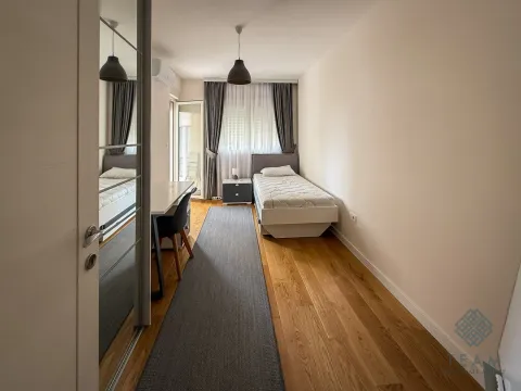 Small bedroom with a single bed, a desk, and a large mirror. - image 10
