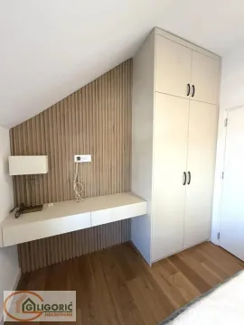 Bedroom with a built-in wardrobe, desk, and wooden wall panels. - image 14