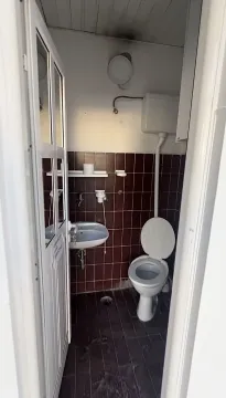 A simple restroom with dark tiles and a sink. - image 4