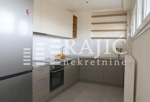 Modern kitchen with beige cabinets and gray countertops.