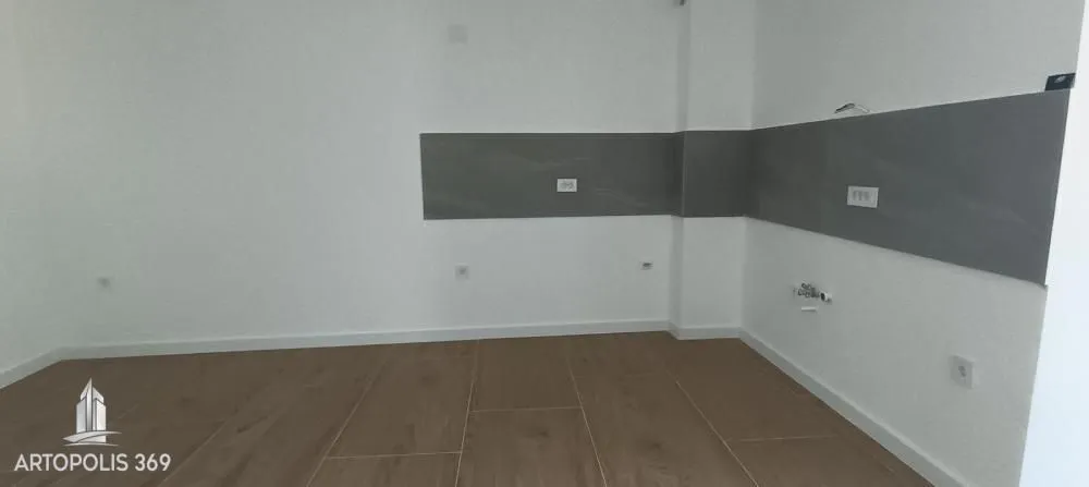 Prazan prostor kuhinje sa pločicama na zidu i podom od keramike u dezenu drveta.