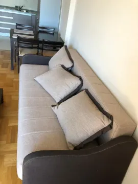 Living room with a sofa and dining area in the background. - image 2