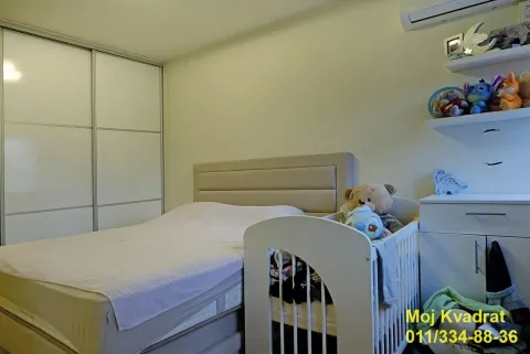 Bedroom with a double bed, baby crib, built-in wardrobe, and shelves. - image 9