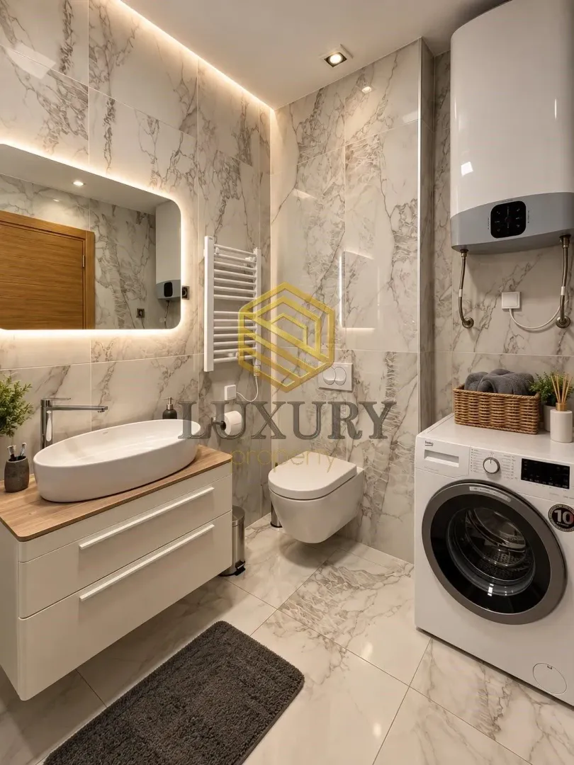 Modernly equipped bathroom with washing machine and marble tiles.
