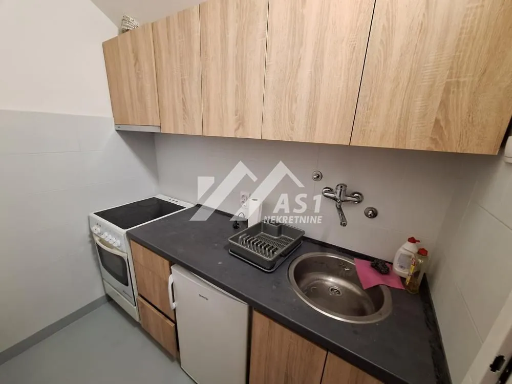 Small kitchen with wooden cabinetry, sink, and stove.