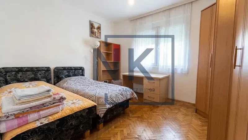 Bedroom with two single beds, a desk, and wooden wardrobes.