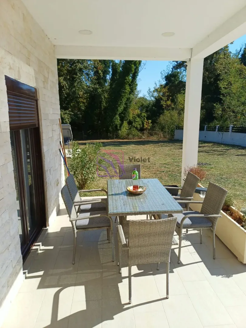 Covered terrace with a dining table and a view of the yard.