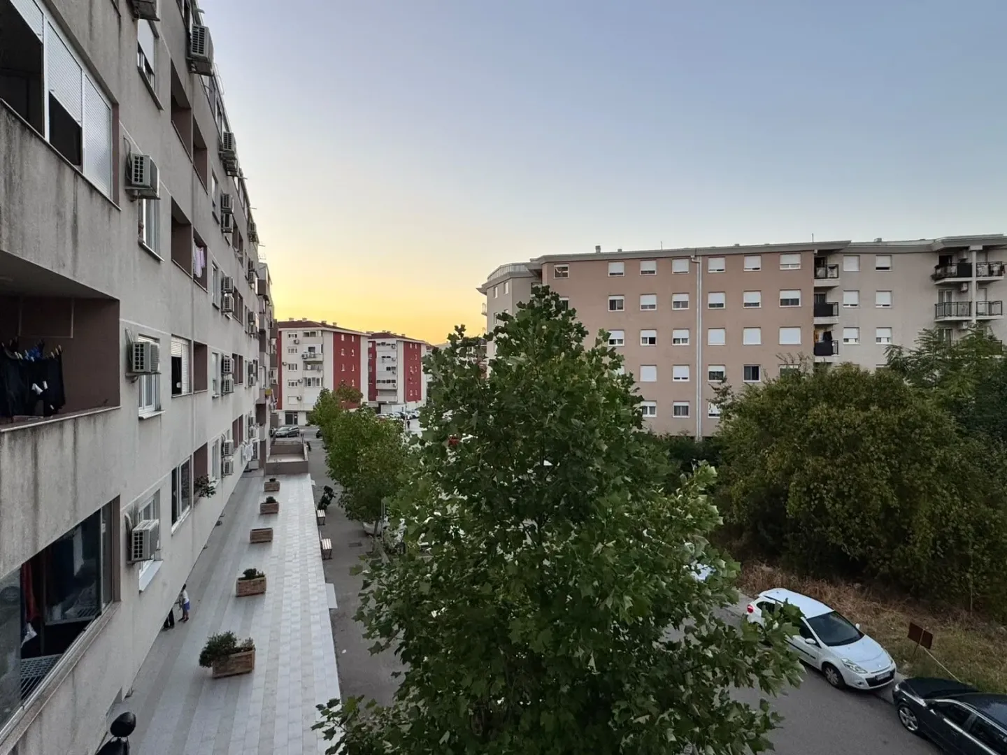 Pogled sa terase na stambene zgrade i okolno naselje u sumrak.