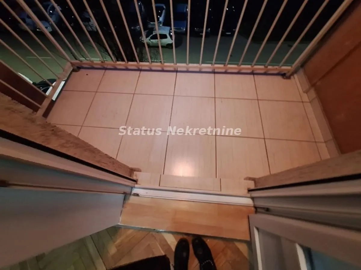 Pogled na popločani balkon sa ogradom noću.