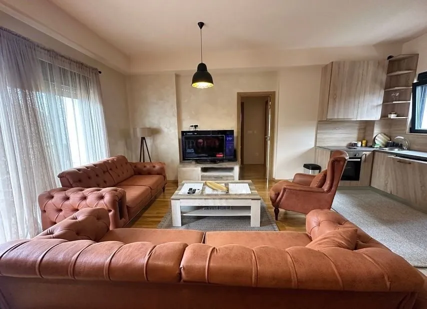 Living room with a sofa set and TV connected to the kitchen.