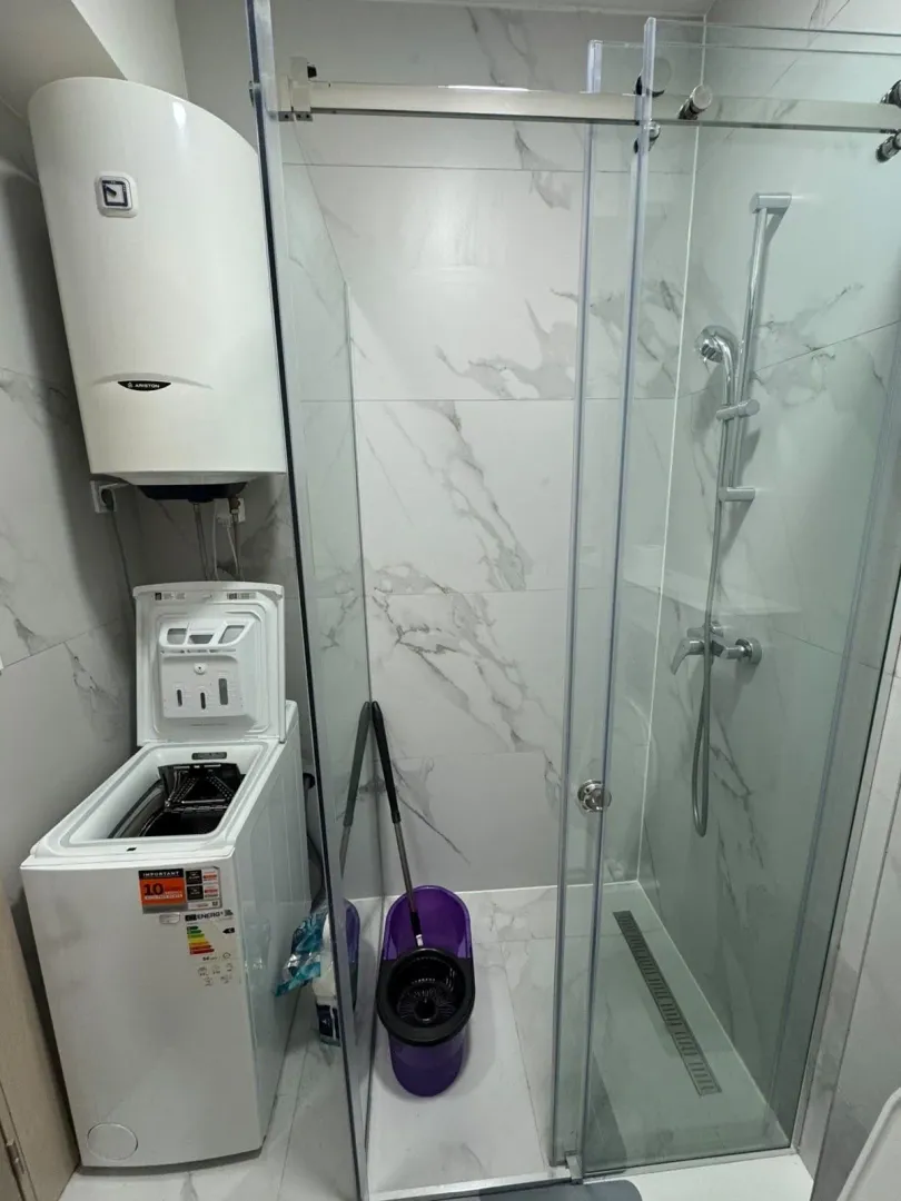 Bathroom with a shower cabin, water heater, and washing machine.