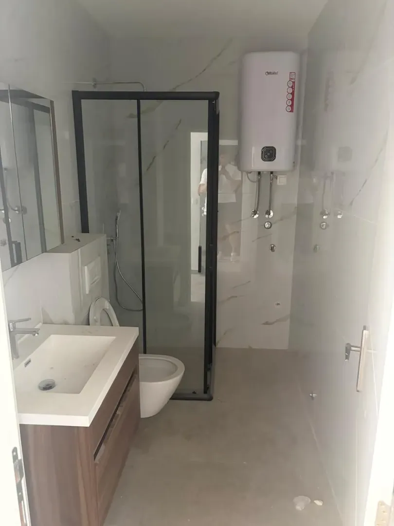 Moderne kupatilo sa tuš kabinom, umivaonikom i bojlerom.