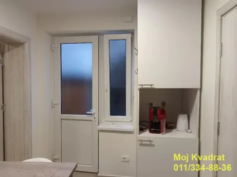 Part of the kitchen with white cabinets, a coffee machine, and a door leading to the terrace. - image 11