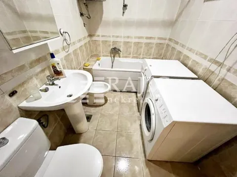 Compact bathroom with a bathtub, washbasin, and washing machine. - image 14