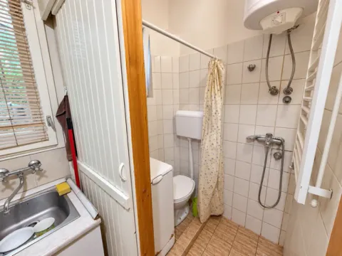 Compact bathroom with a shower area, toilet, and a small sink. - image 9
