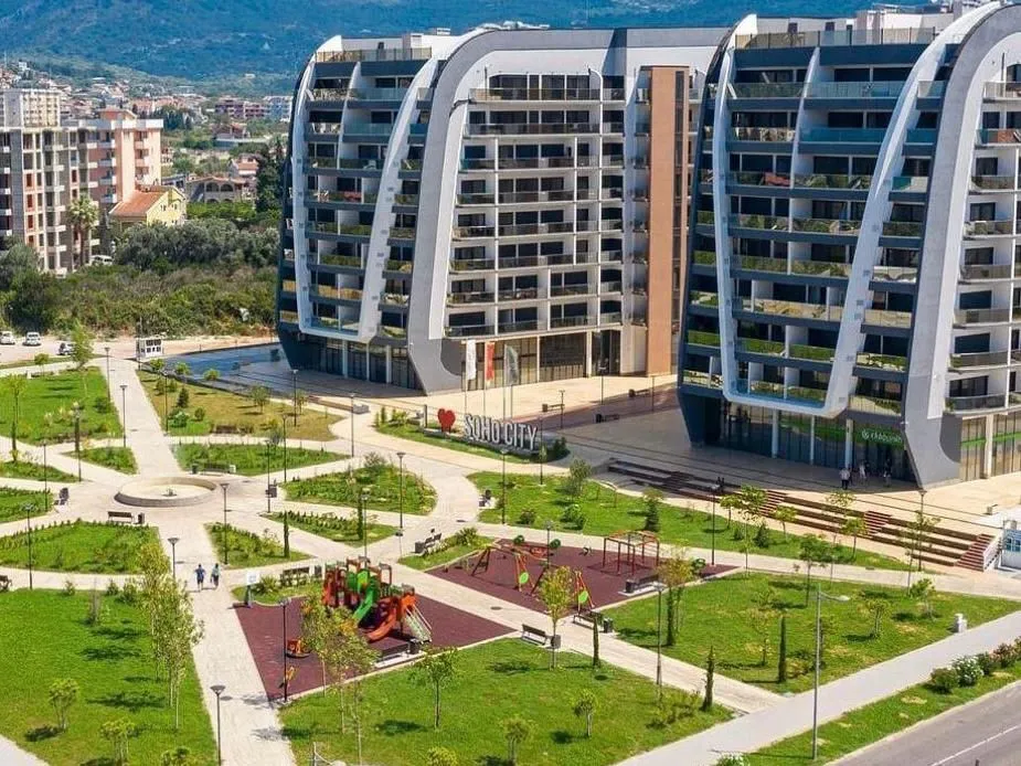 Modern residential buildings with a landscaped courtyard and park within the complex.