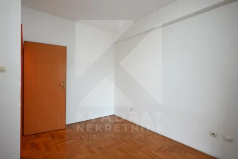 Empty room with white walls, wooden parquet flooring, and a wooden door. - image 8