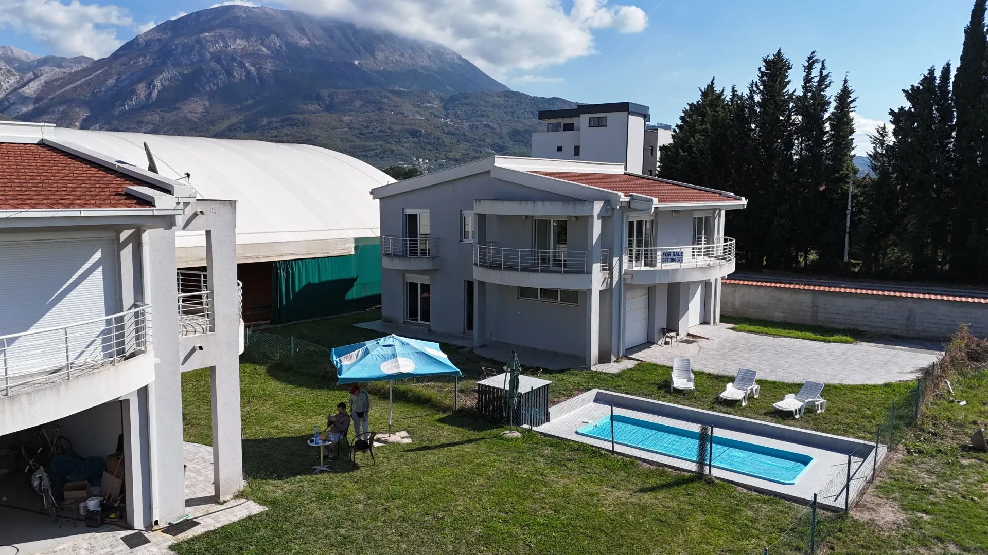 Pogled na dvorište kuće sa bazenom i planinskim pejzažem u pozadini.