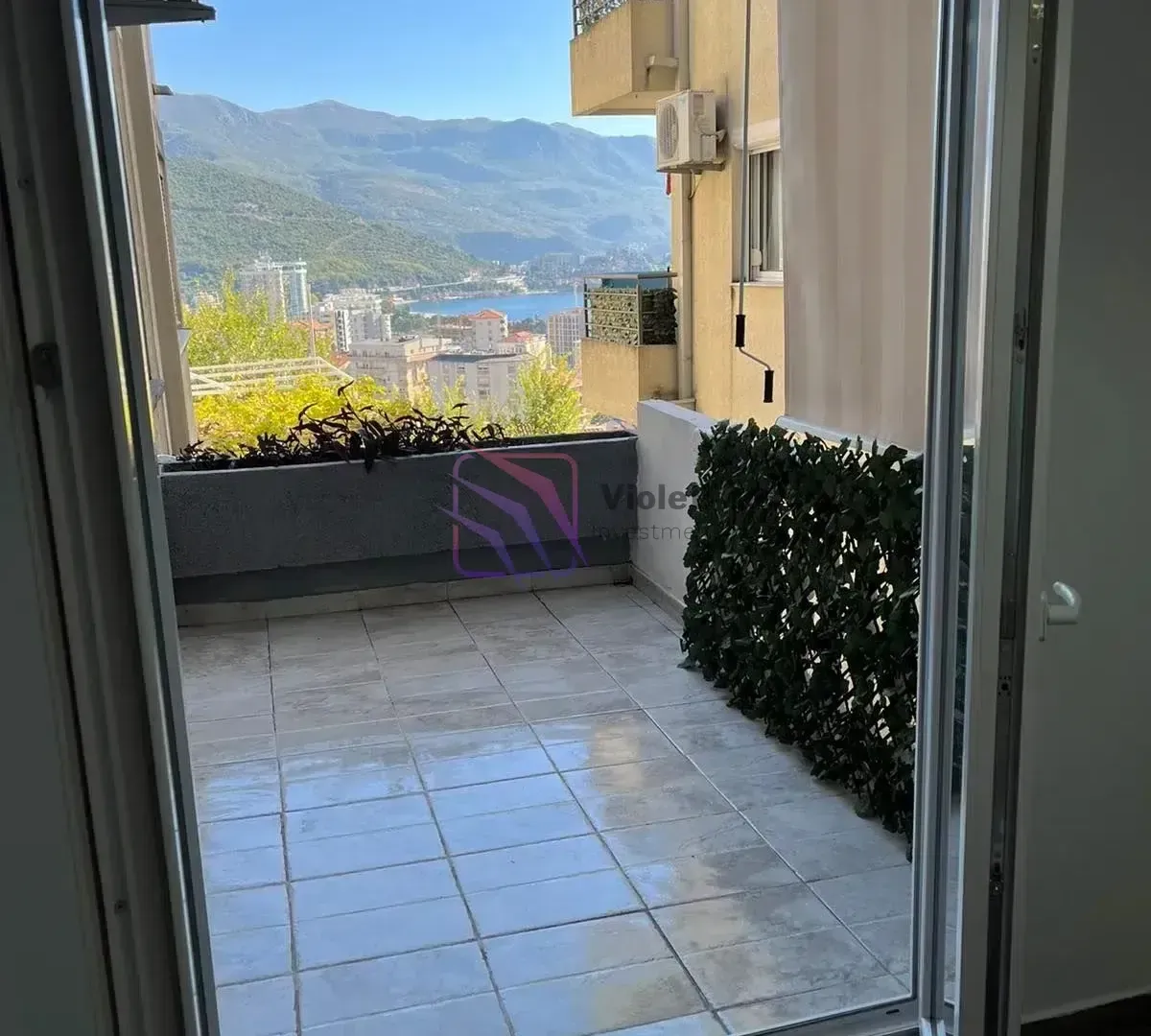 Popločani balkon sa pogledom na grad i planine.
