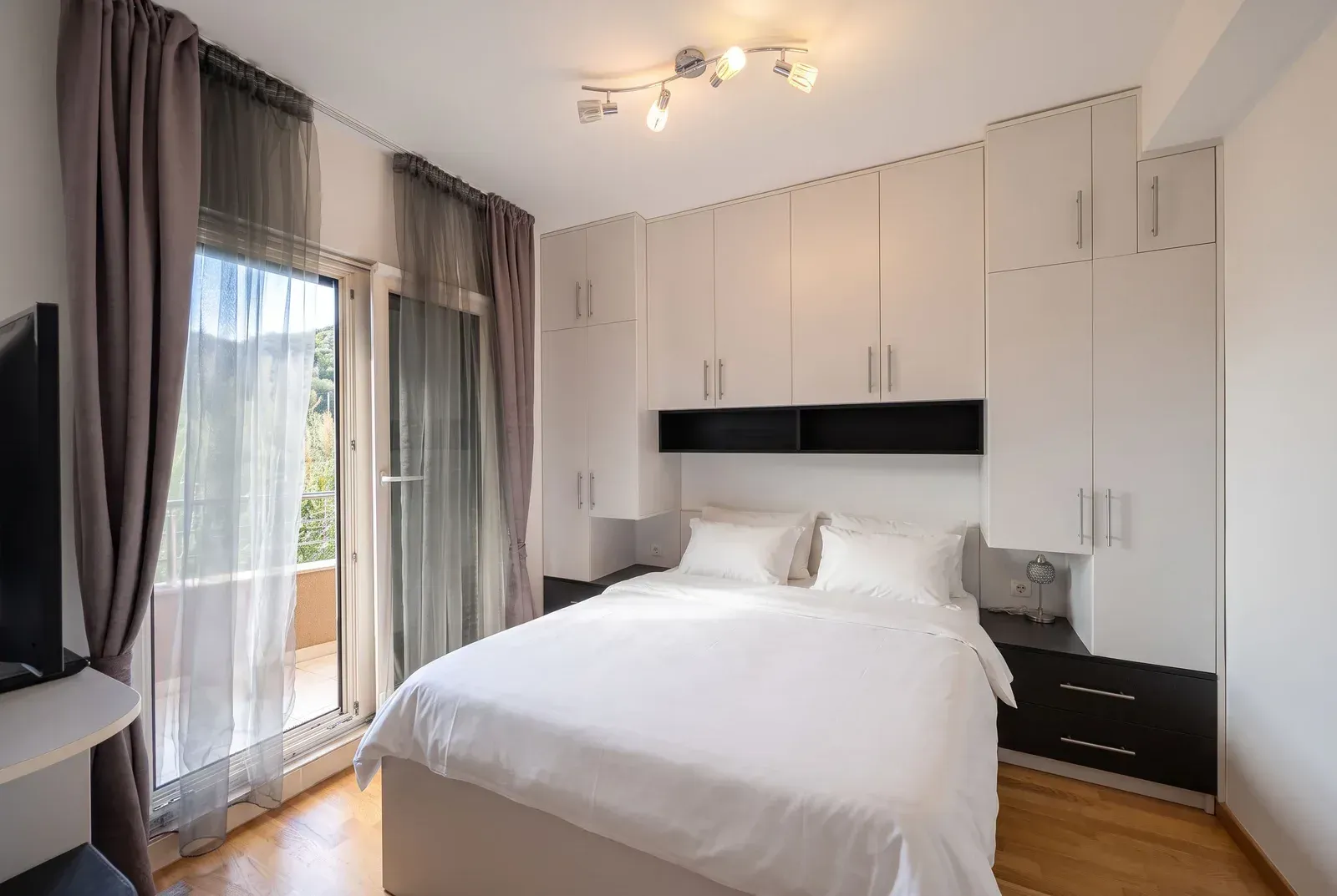 Bright bedroom with a white bed, built-in wardrobes, and access to the terrace.