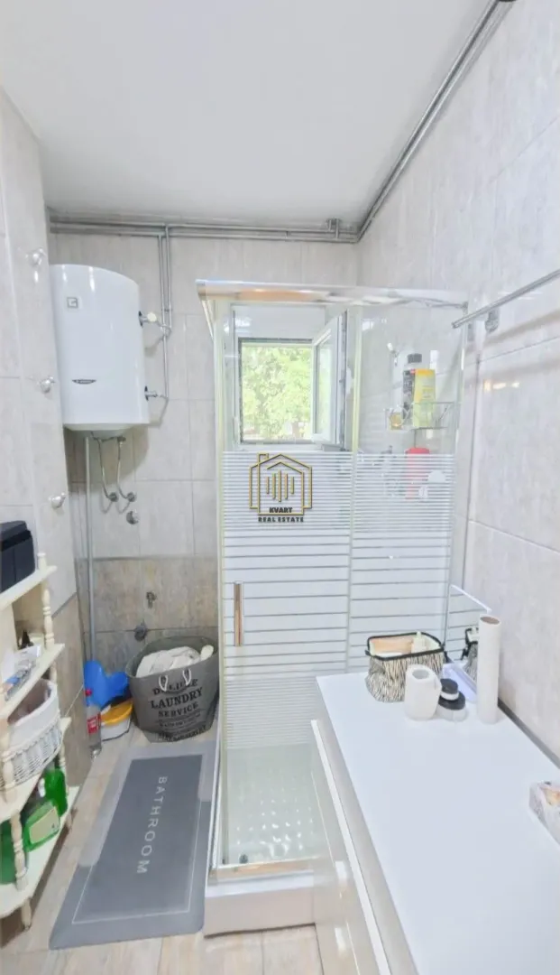 Bathroom with a shower cabin, water heater, and washbasin.