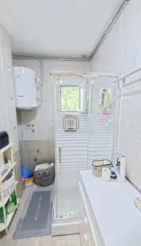 Bathroom with a shower cabin, water heater, and washbasin. - image 9