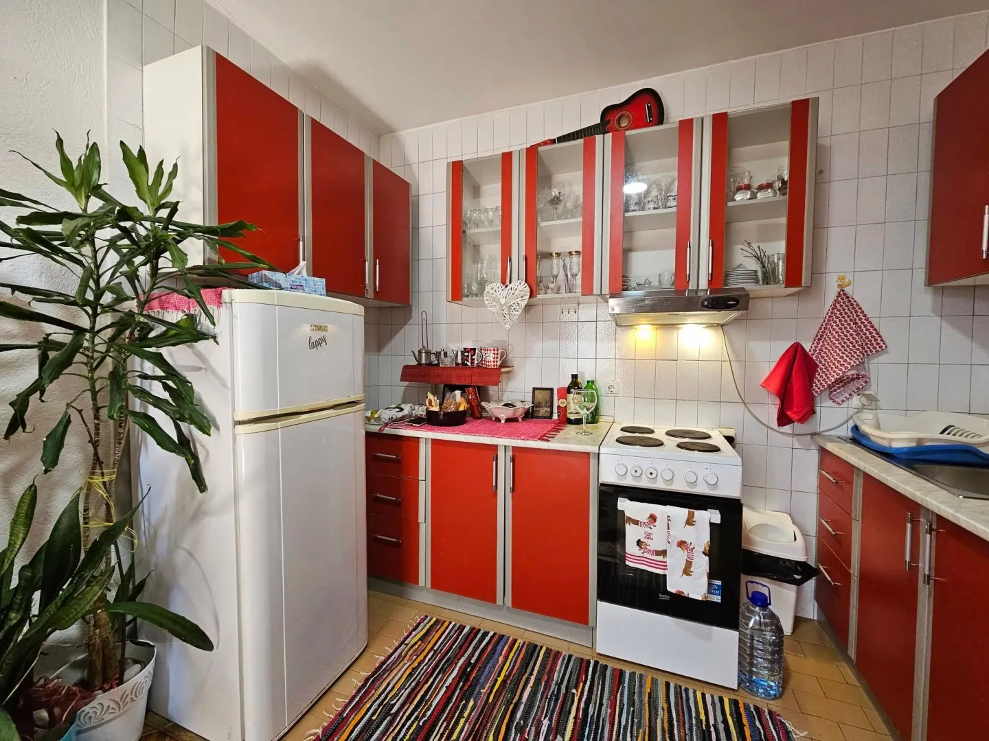 Small kitchen with red cabinets and white appliances.