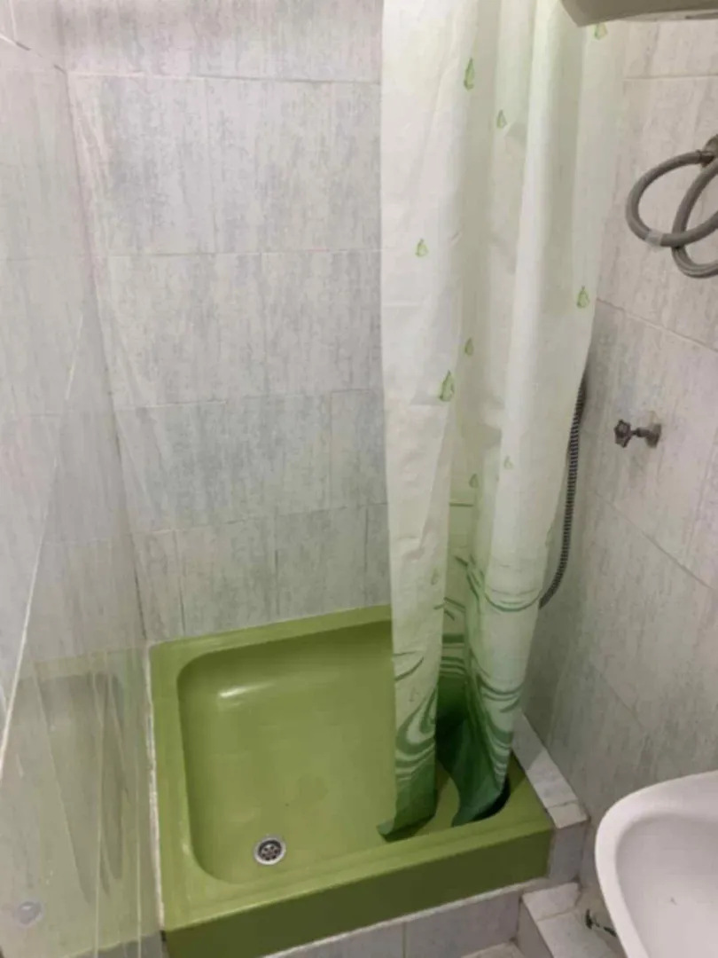 Manje kupatilo sa tuš kabinom i svijetlim pločicama.