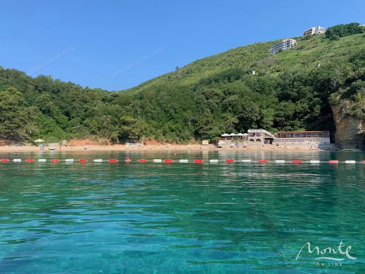 Pogled na more i plažu sa brdima u pozadini.