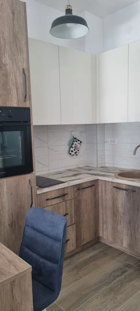 Moderna kuhinja sa drvenim elementima i ugradnom rernom.