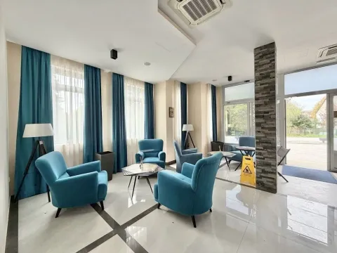 Spacious living room with blue armchairs, large windows, and modern lighting. - image 2