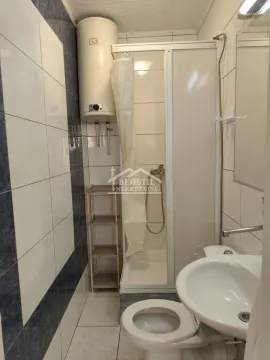 Small bathroom with a shower cabin, washbasin, toilet bowl, and water heater. - image 7