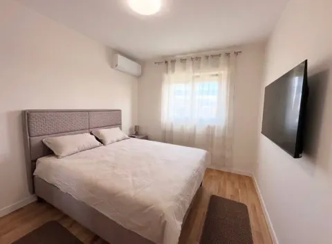 Furnished bedroom with a double bed, air conditioning, and a wall-mounted TV. - image 11