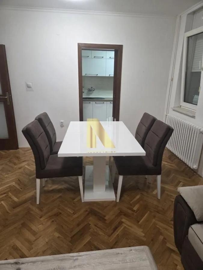 Trpezarija sa stolom i stolicama i pogledom na kuhinju.
