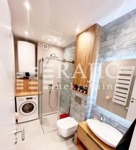 Modernly equipped bathroom with a walk-in shower, washbasin, and washing machine.